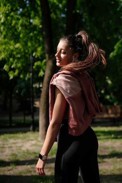 Hermosa joven descansa después de hacer jogging en el parque.