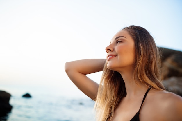 Hermosa joven descansa en la playa de la mañana