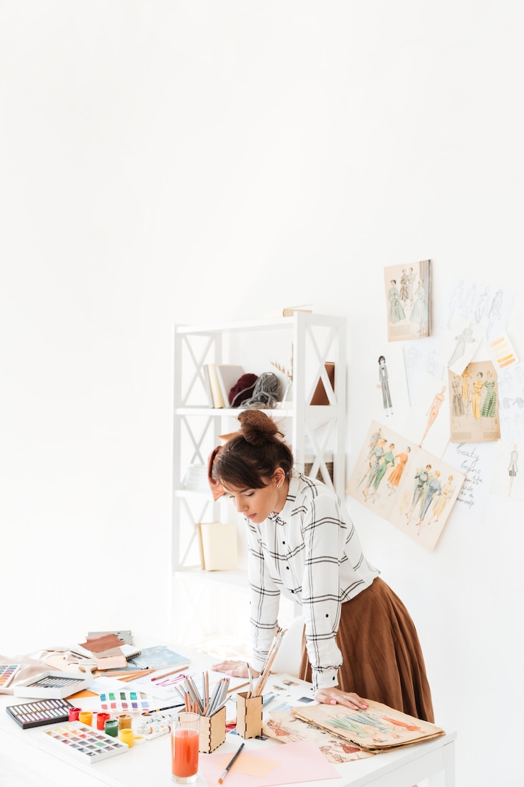 Foto gratuito hermosa joven diseñadora de moda femenina trabajando en estudio