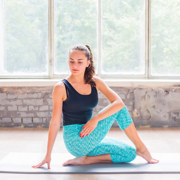 Hermosa joven dong yoga en la estera del ejercicio