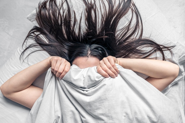 Una hermosa joven duerme en una cama blanca