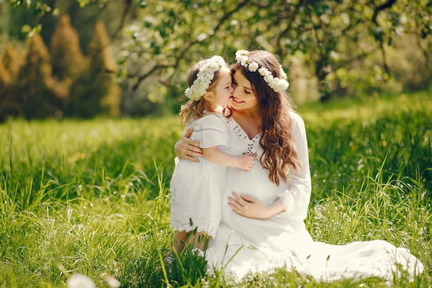 hermosa joven embarazada en un vestido blanco largo jugando con la niña