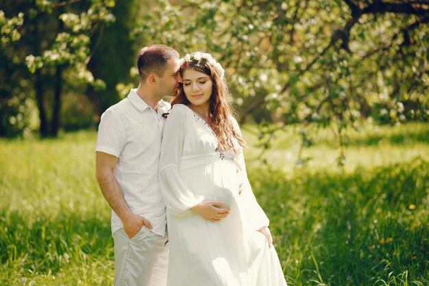 hermosa joven embarazada en un vestido blanco largo con su novio