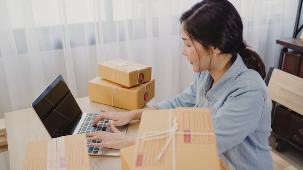 Hermosa joven empresaria asiática inteligente, dueña de una mujer de negocios en línea que comprueba el producto.