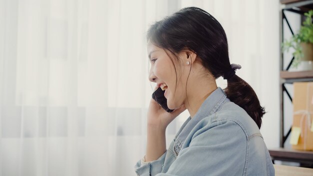 Hermosa joven empresaria asiática inteligente, dueña de una mujer de negocios en línea usando una llamada de teléfono inteligente