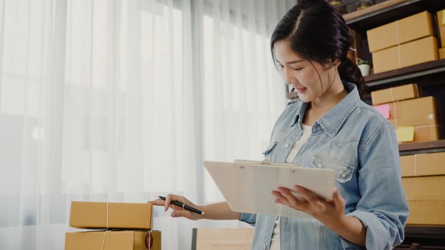 Hermosa joven empresaria asiática inteligente, dueña de una mujer de negocios que comprueba su producto en stock