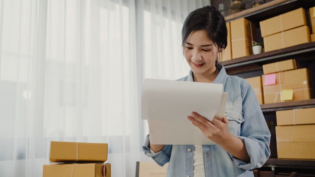 Hermosa joven empresaria asiática inteligente, dueña de una mujer de negocios que comprueba su producto en stock