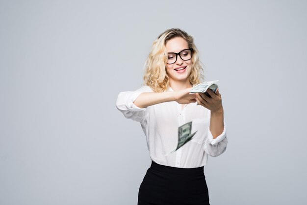 Hermosa joven empresaria esparciendo dinero aislado en la pared blanca