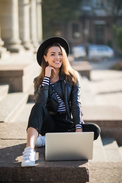 Hermosa joven empresaria estudiante trabaja con su computadora de marca en el centro de la ciudad