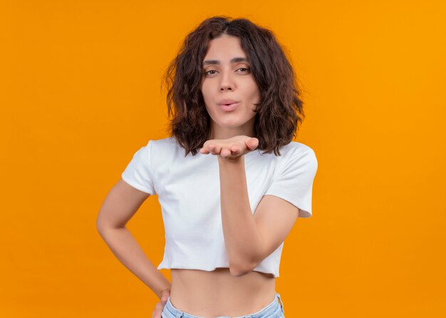 Hermosa joven enviando beso golpe sobre fondo naranja aislado con espacio de copia