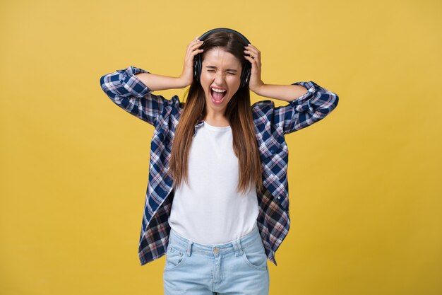 Hermosa joven escuchando música en auriculares sobre fondo de color