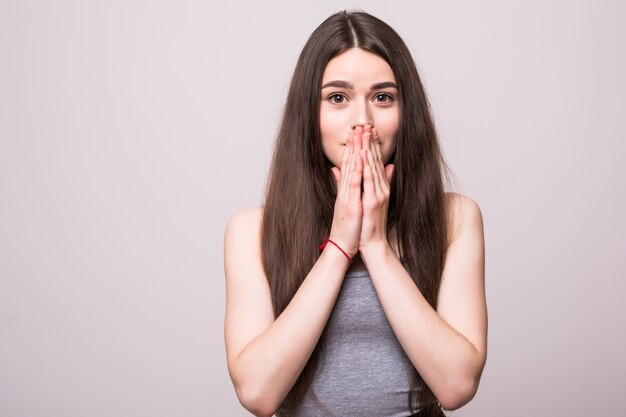 Hermosa joven está conmocionada por las malas noticias, aisladas en una pared gris