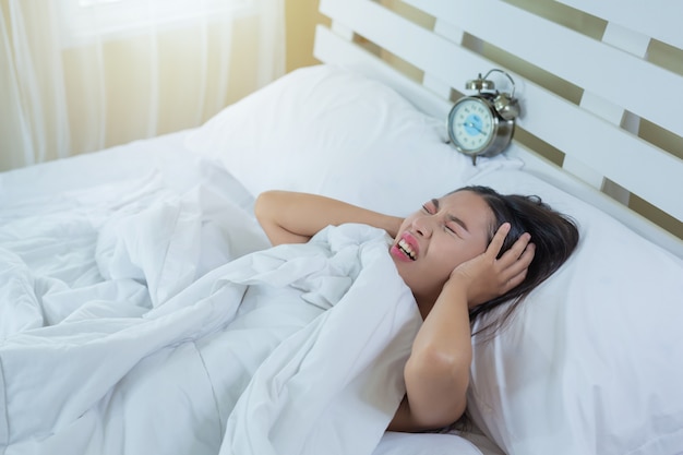 Una hermosa joven está durmiendo y un despertador en el dormitorio de su casa.