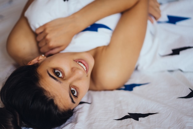 Hermosa joven está durmiendo. Ella se despierta y sonríe. Tiro medio