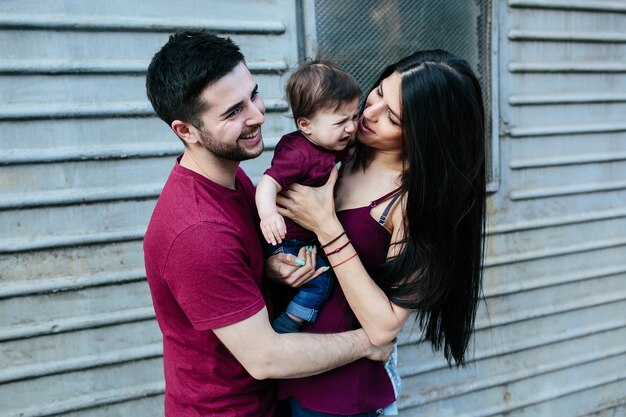 Hermosa joven familia con niño posando en el fondo del edificio