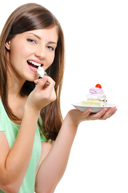 Hermosa joven feliz comiendo pastel sobre fondo blanco.