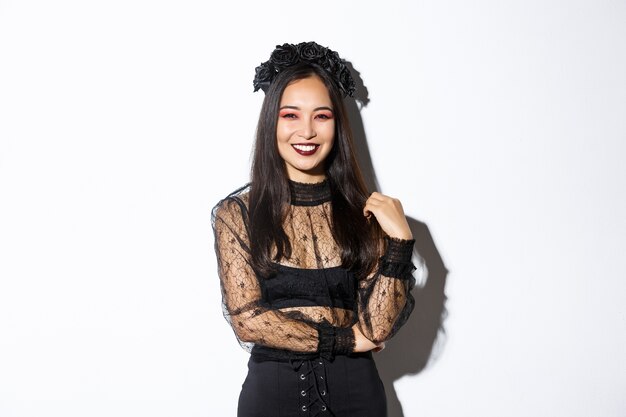 Hermosa joven feliz disfrutando de la fiesta de Halloween, sonriendo y mirando alegre mientras usa su disfraz de bruja malvada para pedir dulces