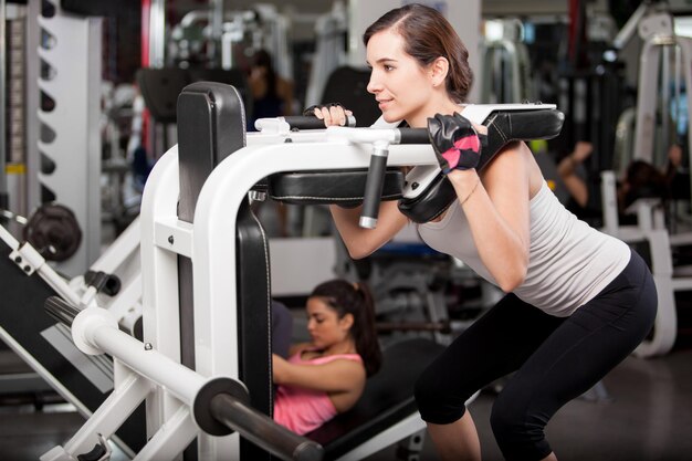 Hermosa joven fortaleciendo sus piernas y haciendo ejercicio en un gimnasio