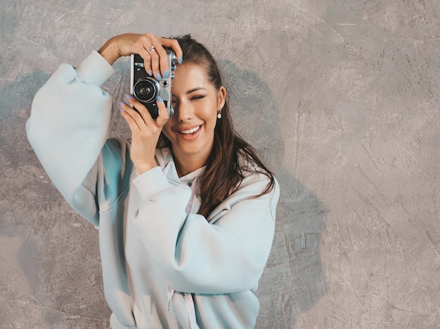 Hermosa joven fotógrafo sonriente chica tomando fotos con su cámara retro. Mujer haciendo fotos.