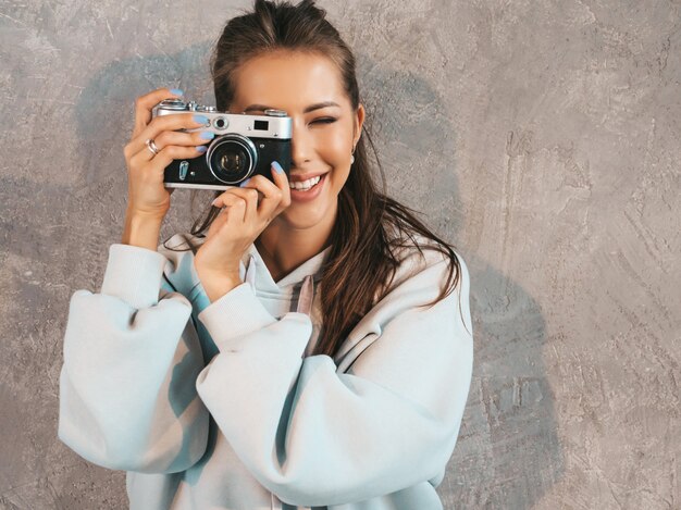 Hermosa joven fotógrafo sonriente chica tomando fotos con su cámara retro. Mujer haciendo fotos.