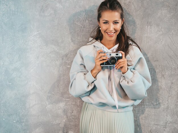 Hermosa joven fotógrafo sonriente chica tomando fotos con su cámara retro.