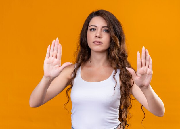 Hermosa joven gesticulando no en la pared naranja aislada