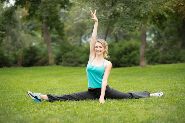 Hermosa joven haciendo ejercicios de estiramiento en el parque.