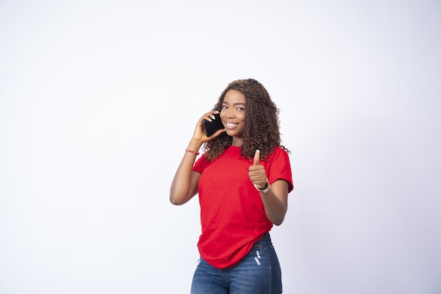 Hermosa joven haciendo una llamada telefónica dando un pulgar hacia arriba