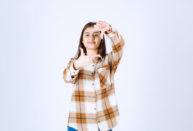 Hermosa joven haciendo marco con las palmas de las manos y los dedos.