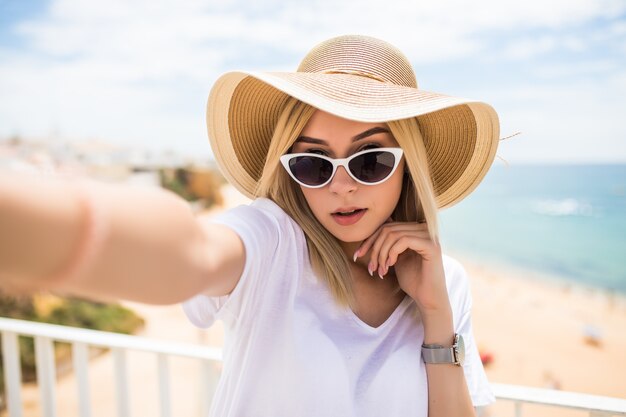 Hermosa joven haciendo selfie en teléfono en la vista de la playa