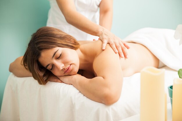 Hermosa joven hispana que se queda dormida mientras una masajista le da un masaje muy relajante en un spa