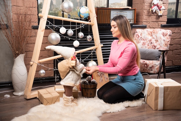 Hermosa joven jugando con muñeca en casa.