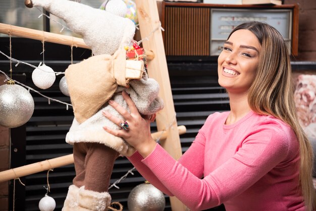 Hermosa joven jugando con muñeca en casa.