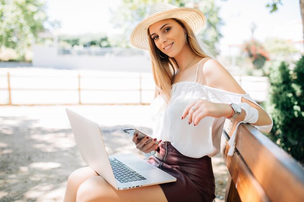 Hermosa joven con laptop en el parque de verano