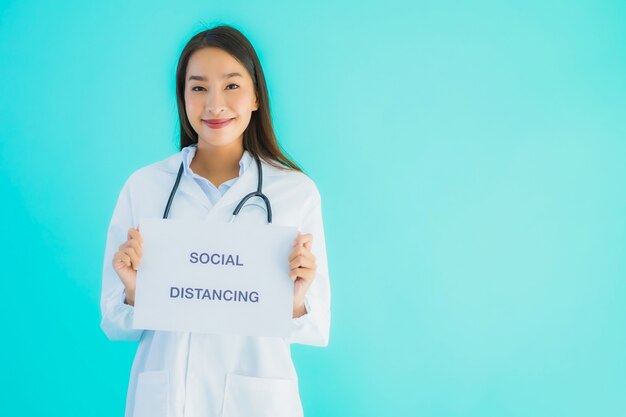 Hermosa joven médico asiático mujer con papel de signo con distanciamiento social