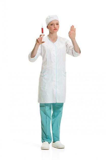 Hermosa joven médico en bata médica con jeringa en la mano.