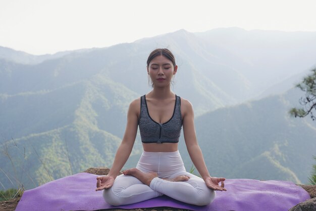 Hermosa joven meditando y haciendo ejercicio encima de él.