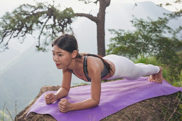 Hermosa joven meditando y haciendo ejercicio encima de él.