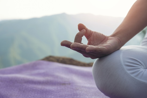 Hermosa joven meditando y haciendo ejercicio encima de él.