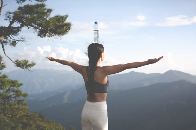 Hermosa joven meditando y haciendo ejercicio encima de él.