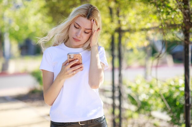 Hermosa joven mirando su teléfono y sintiéndose triste