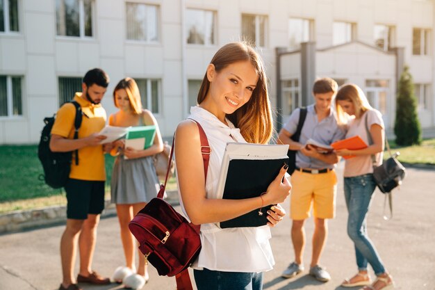 Hermosa joven con mochila de terciopelo rojo con libros