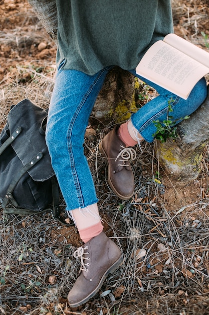 Hermosa joven morena sentarse bajo el árbol leer libro