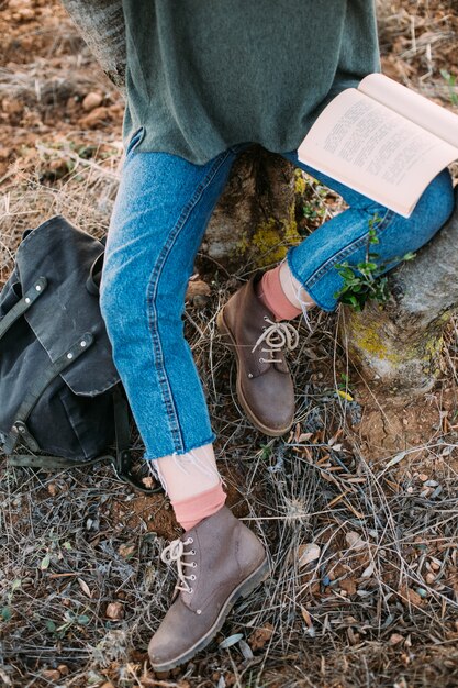 Hermosa joven morena sentarse bajo el árbol leer libro