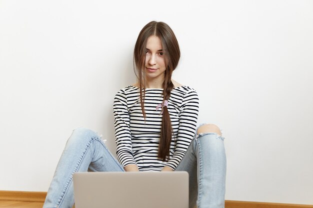 Hermosa joven mujer caucásica con peinado desordenado usando laptop genérica