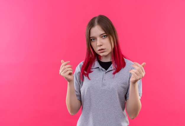 Hermosa joven mujer vistiendo camiseta gris levantando las manos sobre la pared rosa aislada con espacio de copia