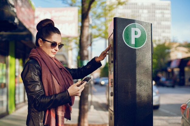 hermosa joven paga por el estacionamiento en metro en la calle