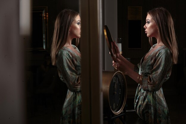 Hermosa joven parada frente al espejo y mirándose a sí misma