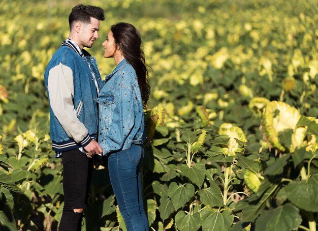 Hermosa joven pareja en el amor de pie en un campo de girasoles.