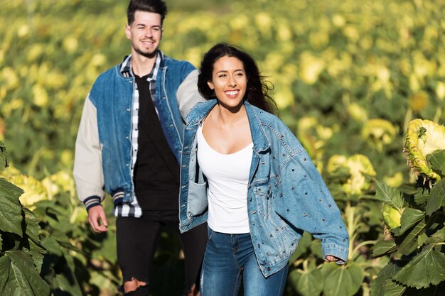 Hermosa joven pareja en el amor de pie en un campo de girasoles.